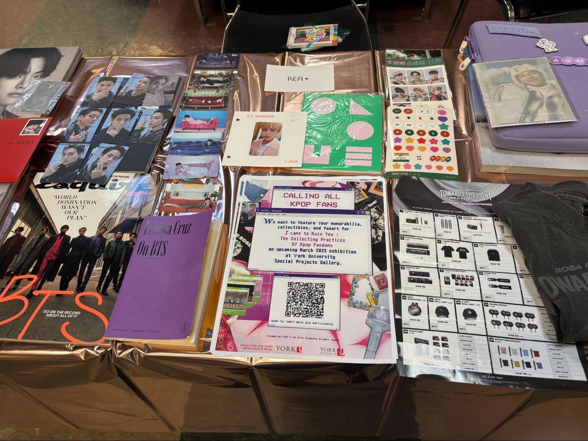 Photo of a table full of collected Kpop items, including photographs, zines, and books.