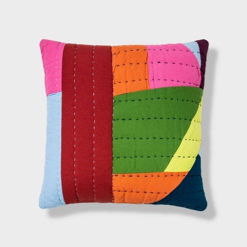 Image of a pillow from the Gee's Bend Target collaboration with fabric printed with a colorful block pattern (red, pink, orange, green, yellow, blue) and then horizontal and vertical stitches made on top of it.
