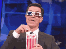 Stephen Colbert eats popcorn and wears 3-D glasses. 
