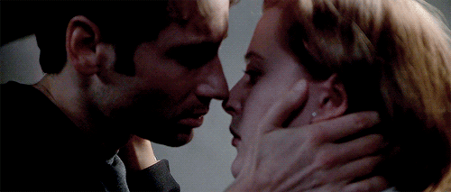 Animated gif of Mulder and Scully almost kissing and then the caption "Ow, Jesus!"