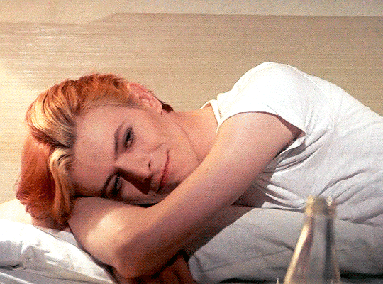 Animated gif of David Bowie from The Man Who Fell To Earth. He's resting on his side, arms tucked under his head, and smiles as he raises his eyebrows.