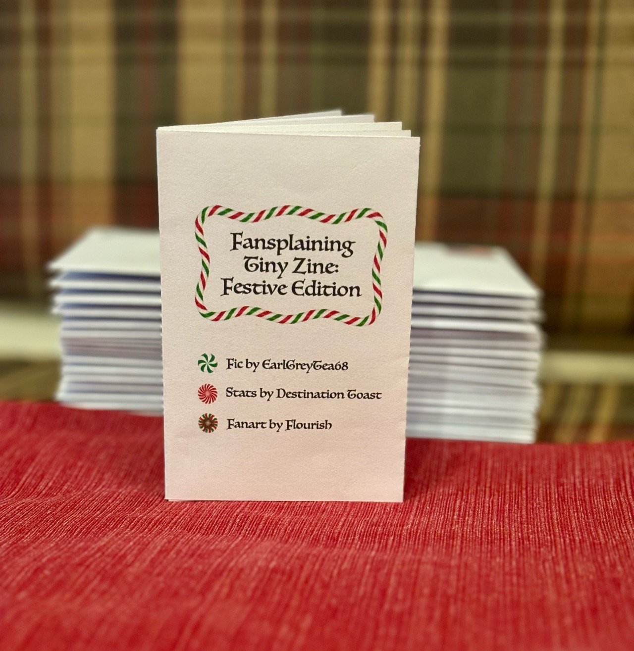 Photograph of a stack of festive tiny zines and one upright