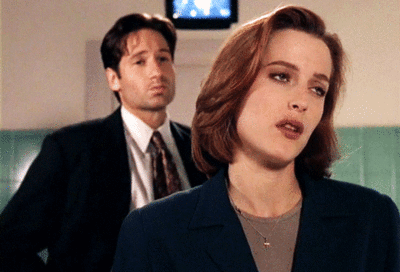 Animated gif of Scully rolling her eyes with Mulder in the background