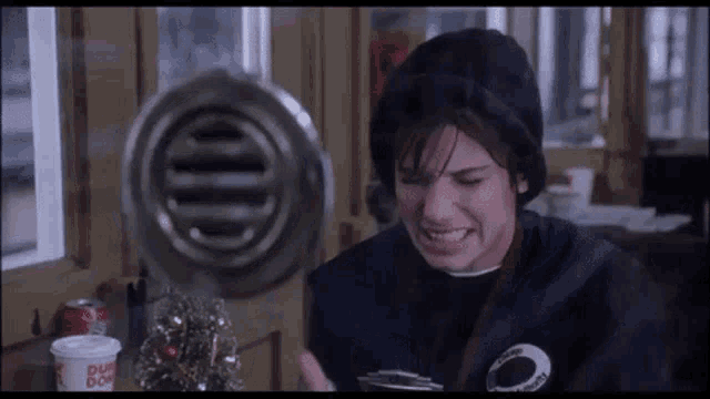 Animated gif of Sandra Bullock from While You Were Sleeping sitting in her ticket booth, hitting herself in the head.
