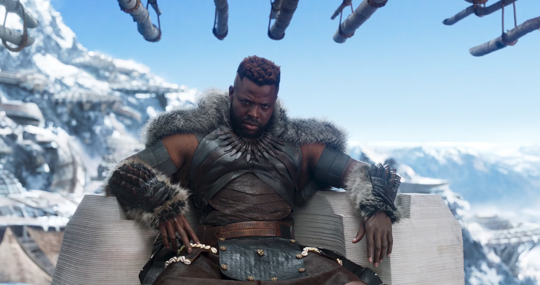 A still from Black Panther featuring M'Baku sitting on a chair/throne, backdropped by snow-covered mountains.