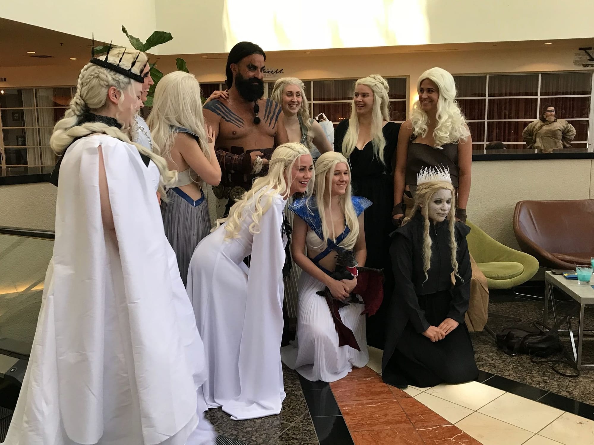 Image of a set of Daenerys cosplayers surrounding a single Khal Drogo cosplayer in a hotel lobby