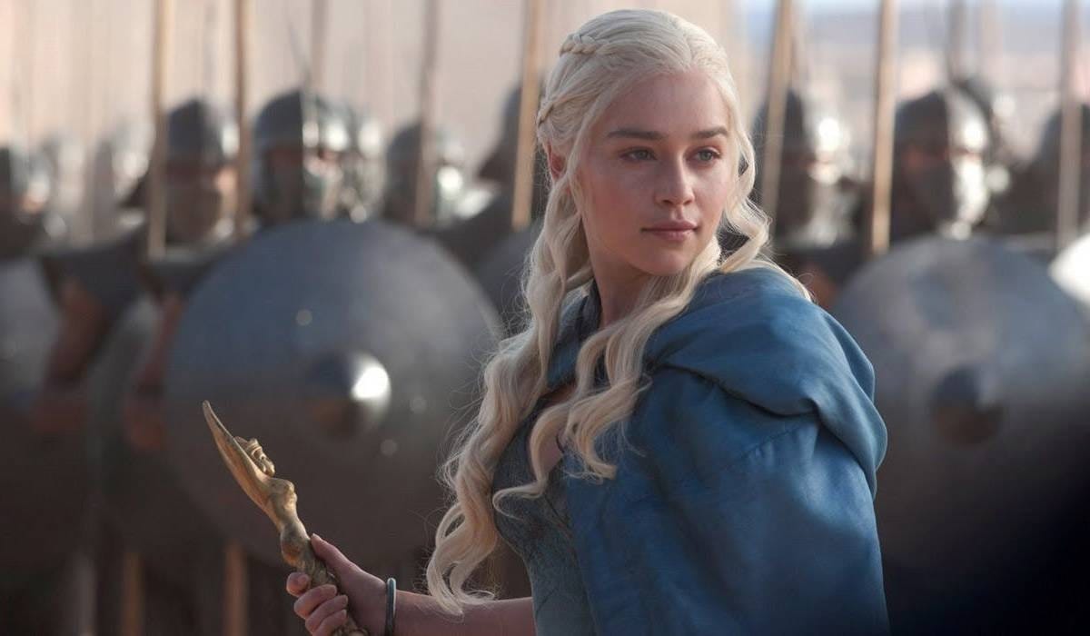 Image of Daenerys in a blue cloak standing in front of a an army holding shields and swords.