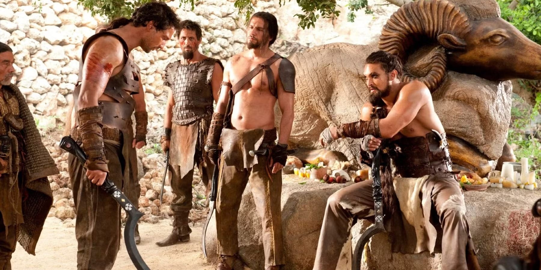Image of Dothraki characters greeting each other, a giant statue of a ram in the background.