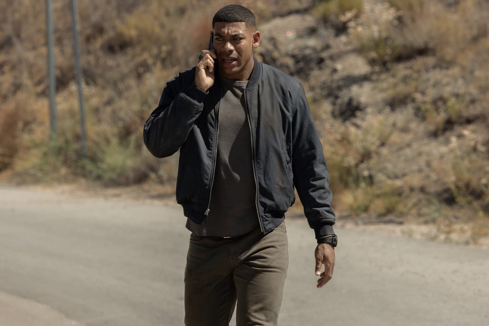 Production still of John walking down a road talking on a cell phone