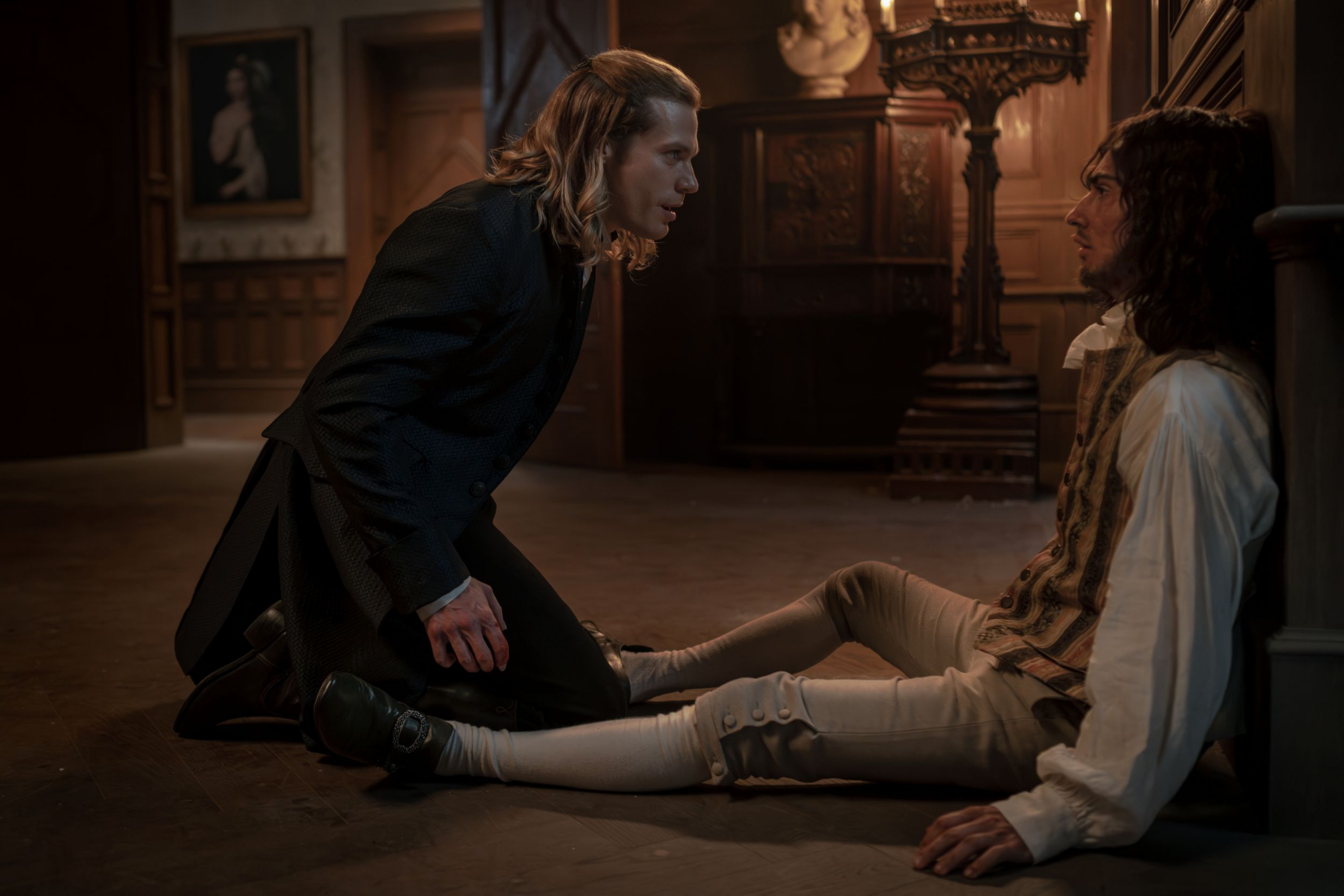 Production still featuring a now vampire Lestat leaning over his brother, who is backed up against the wall.