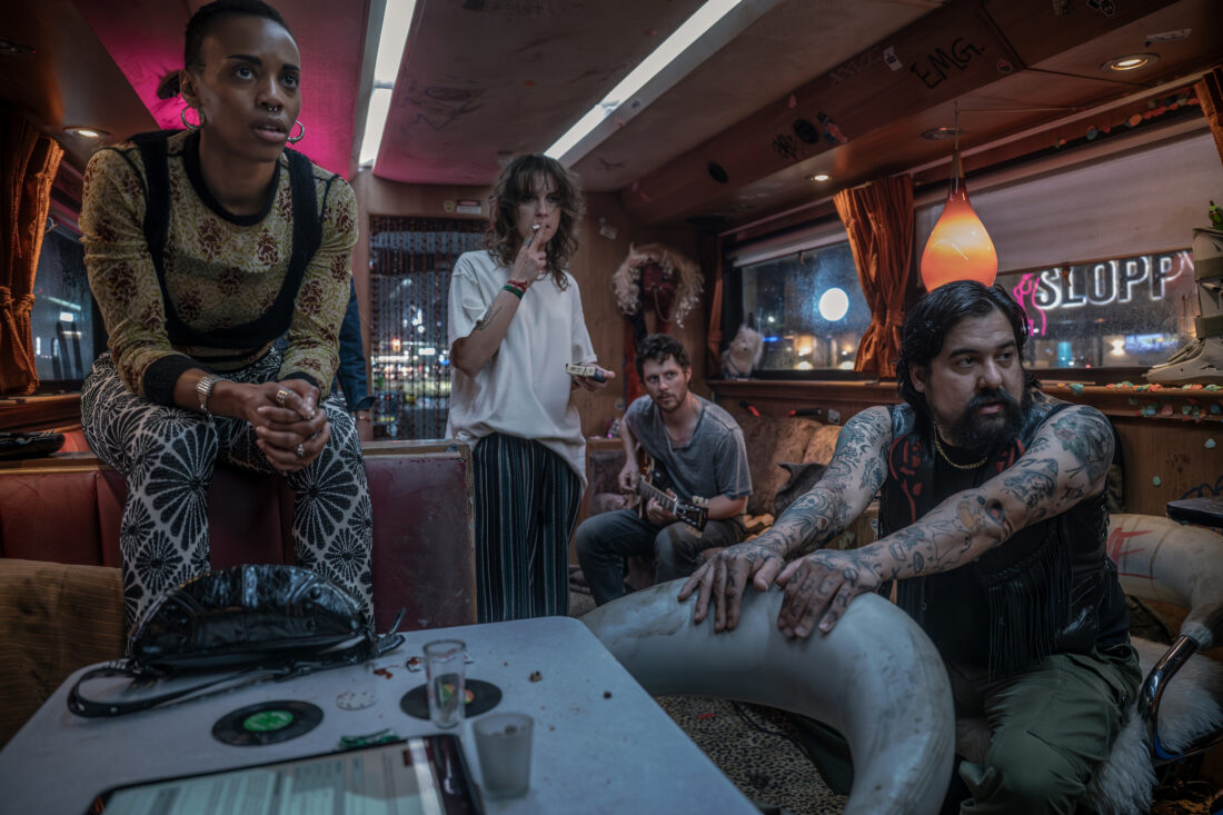 Production still featuring Dee, TC, Larry, and Salamander on the tour bus.
