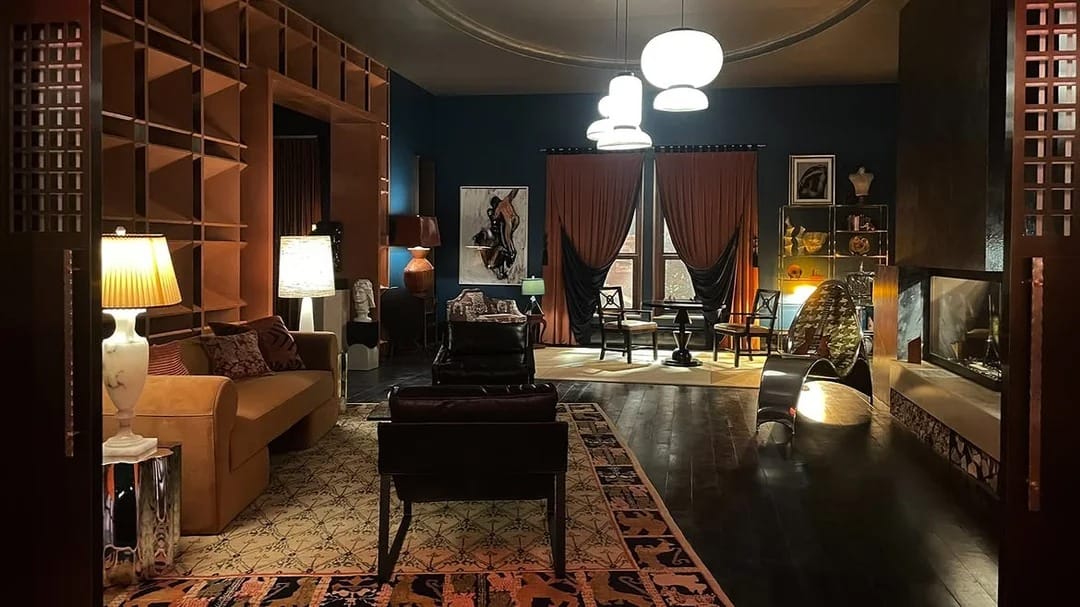 Image from TVL featuring Lestat's apartment, with two chairs and a couch in the foreground, and a sitting area in the distance.