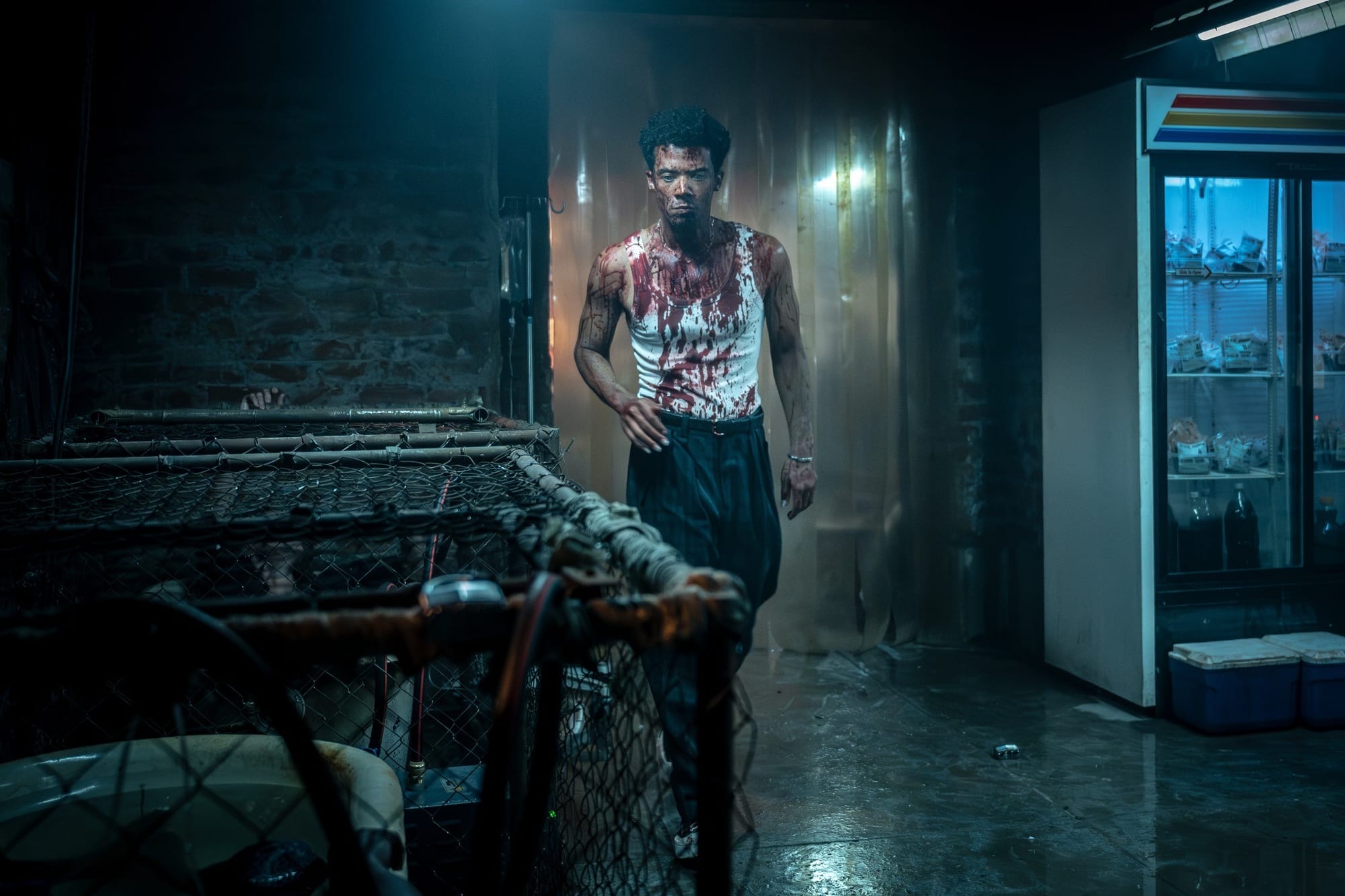 Production still featuring Louis covered in blood entering the room where the human prisoners are being kept by the Fang Gang in caged bathtubs.