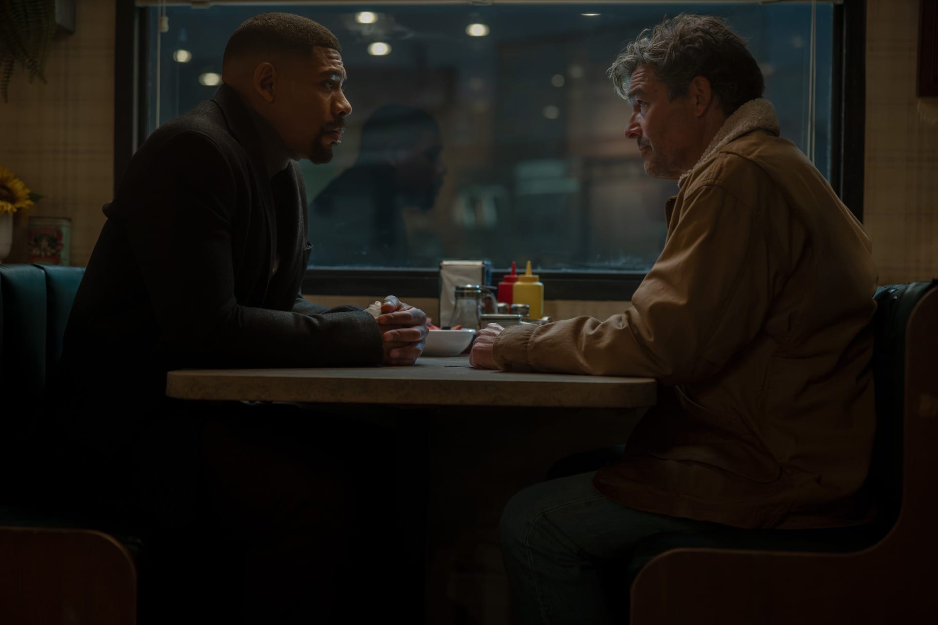Production still of John and Hall sitting at the diner at night.