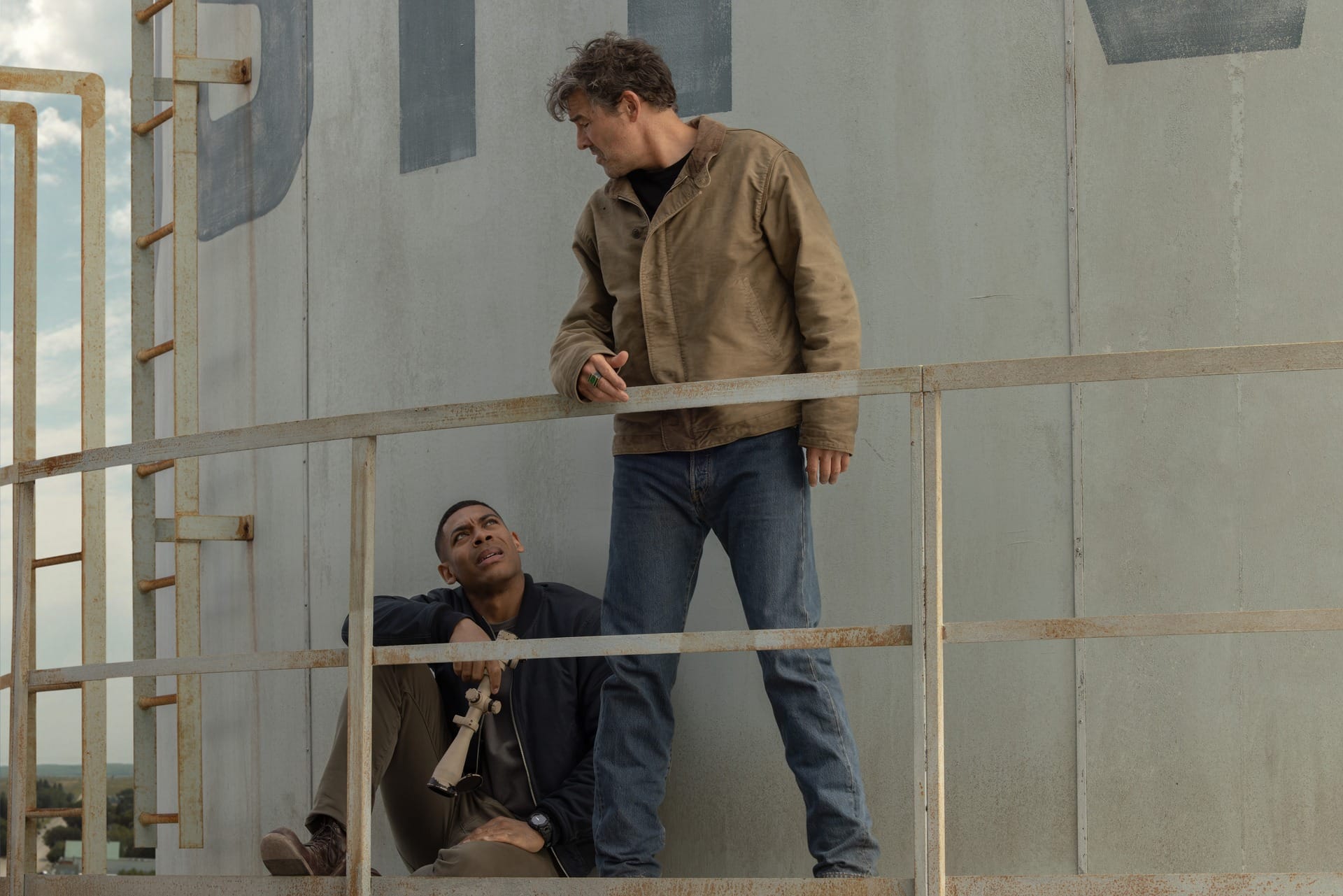 Production still of John (seated) and Hal (standing) on the platform of a water tower.