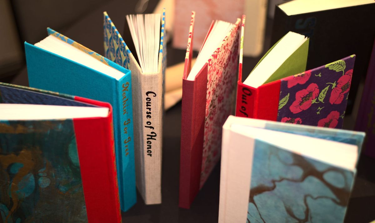 Photograph of a collection of colorful fanbound books, stood up on a table in a semi-circle.
