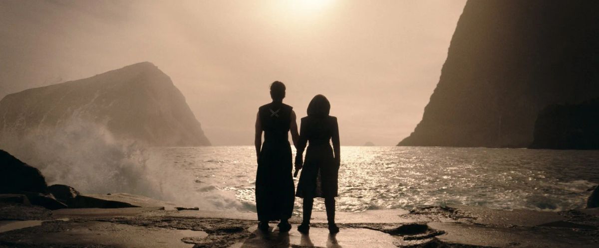 Still from The Acolyte featuring Qimir and Osha sillouetted in the sunset gazing out at the ocean.