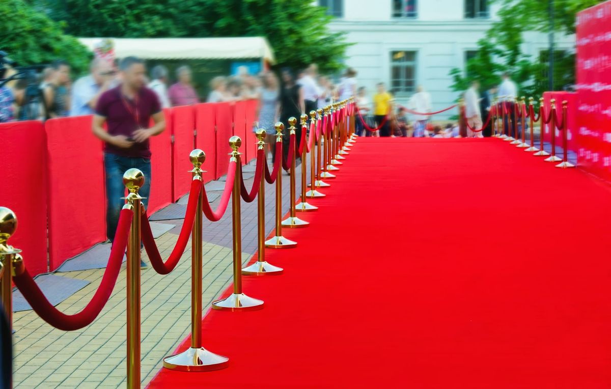 Photograph of a red carpet and a long line of red ropes.