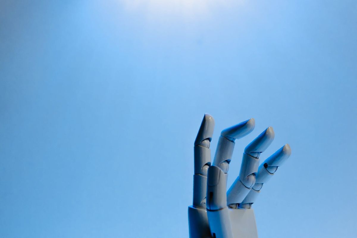 A robot hand reaching upwards against a blue background.