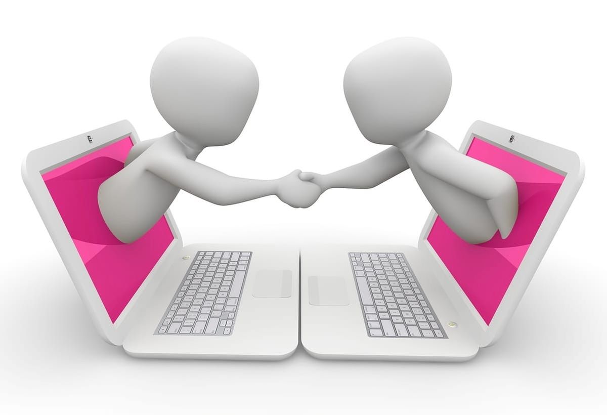 Two faceless white figures coming out of white laptops with pink screens and shaking hands.