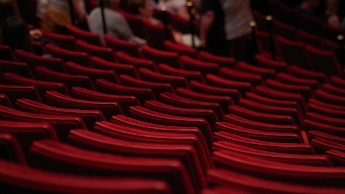 Photograph of rows of red theatre seats.