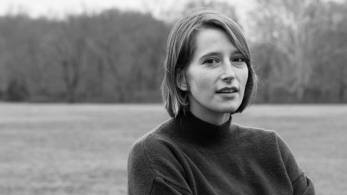 Black and white photograph of Kaitlyn Tiffany standing in a field.