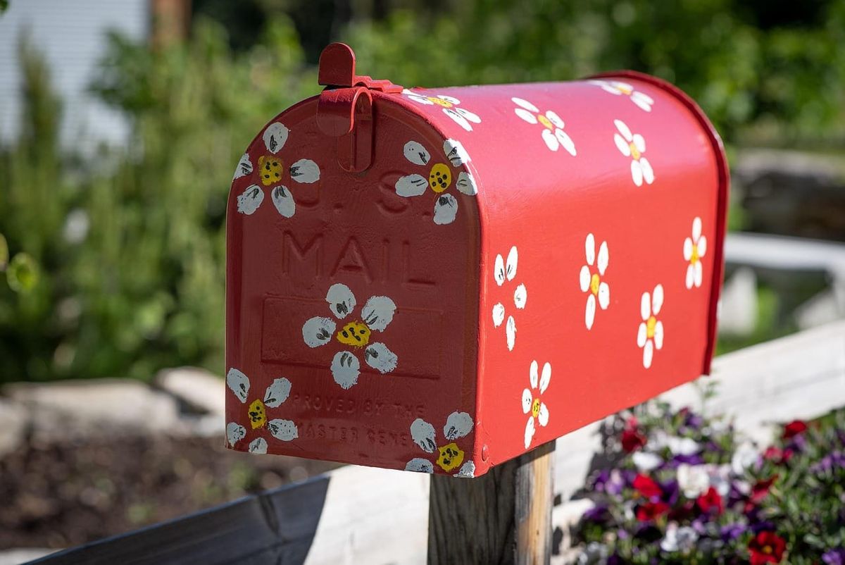Photograph of a red mailbox with painted white and yellow flowers.