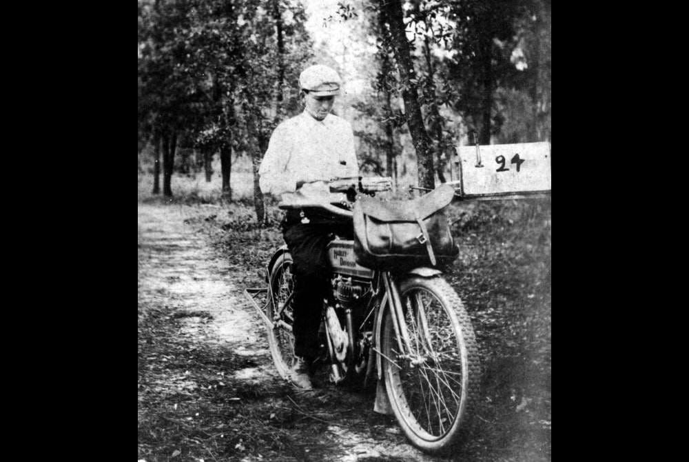 Black and white archival image of a mail carrier on a bicycle