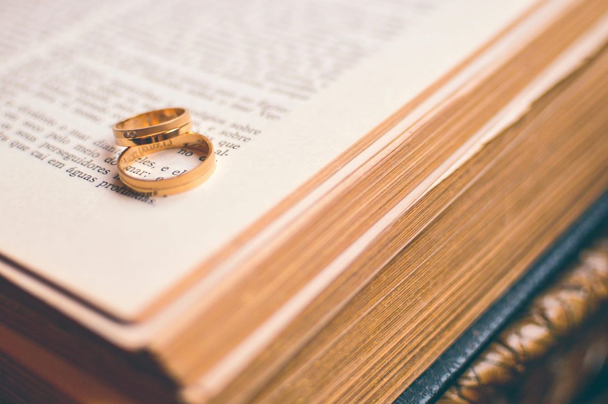 Photograph of a pair  of gold rings sitting on the page of an open book