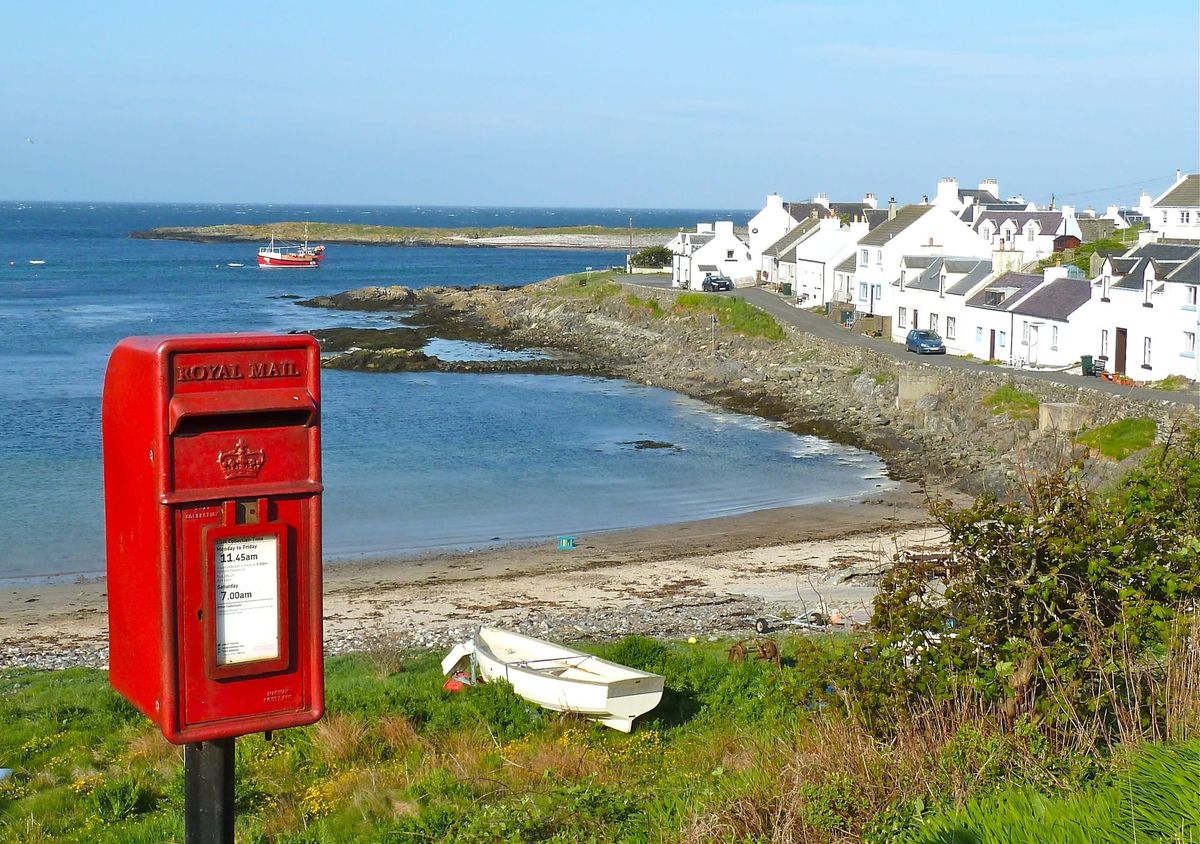 Photograph of seaside town with a red Royal Mail postbox in the foreground.