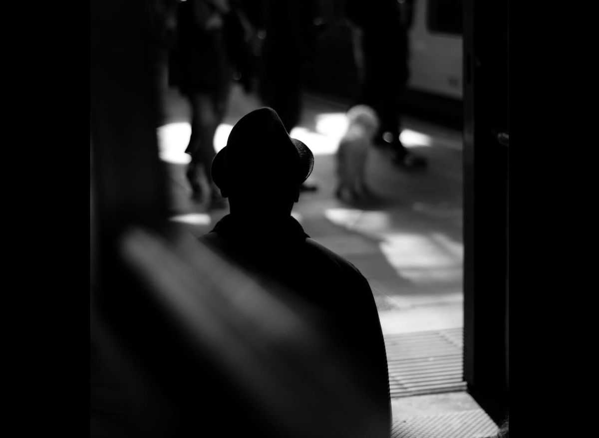 Black and white photo of the outline of a shadowy figure in a fedora.