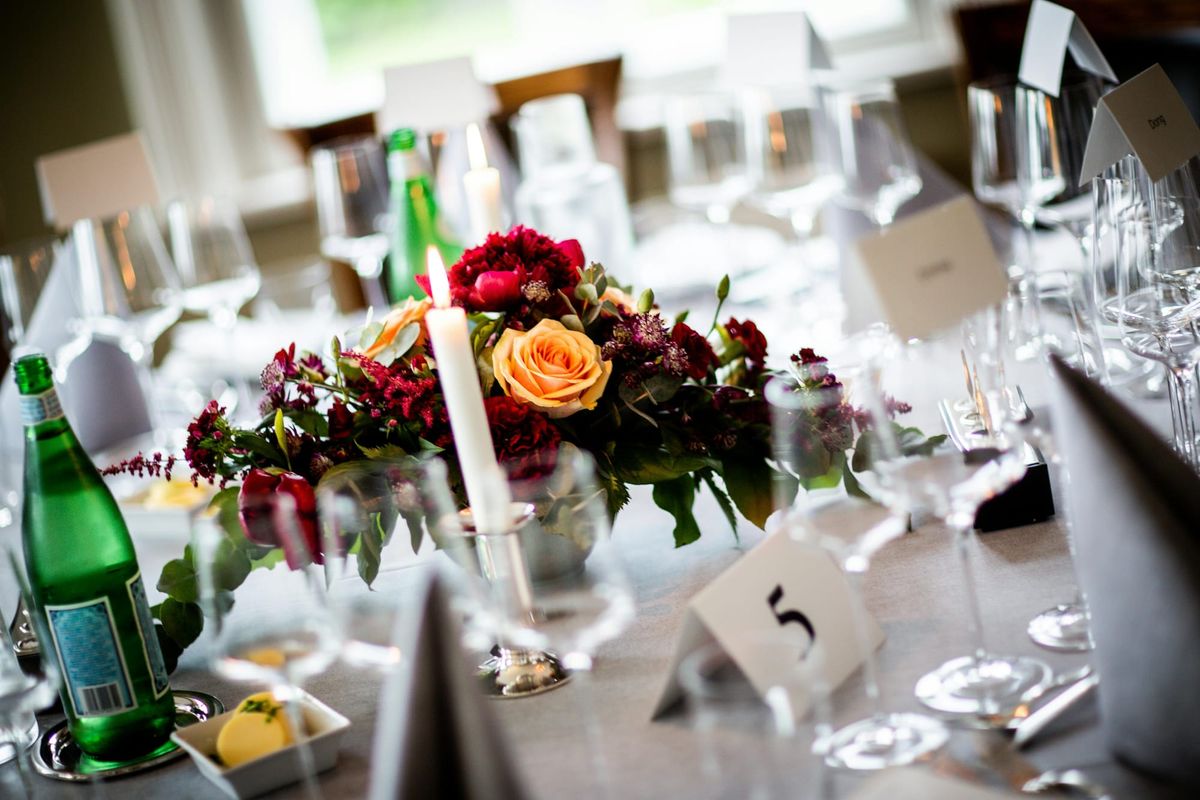 Photograph of the a floral centerpiece and place settings at a wedding reception.