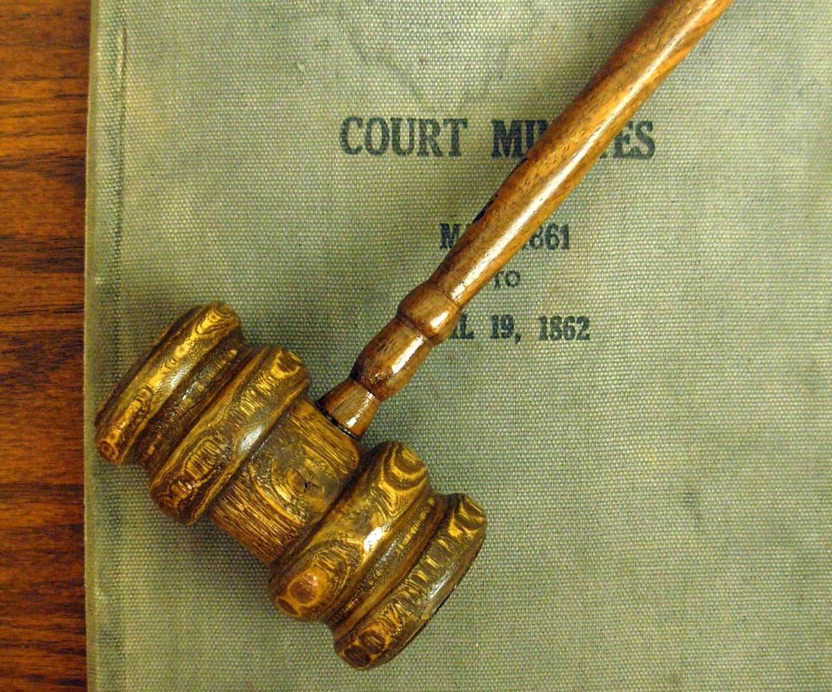 A gavel rests across a law book. 