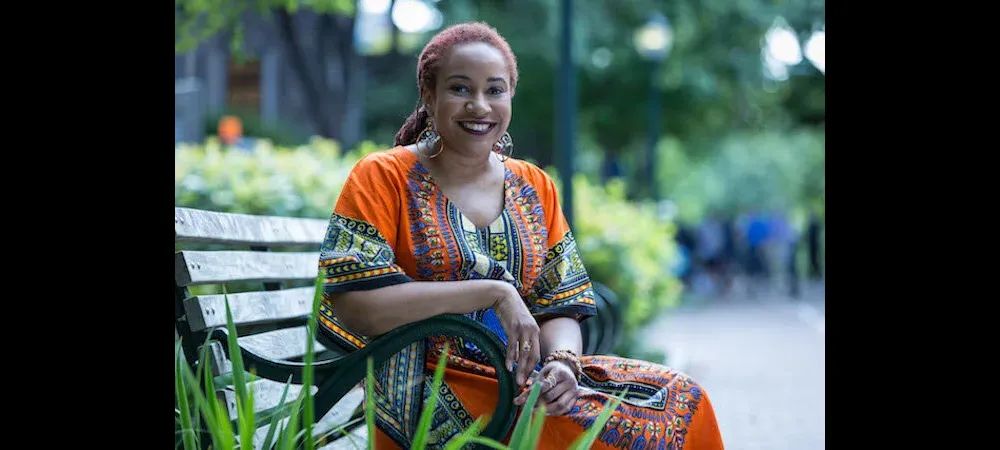 A portrait of Ebony Elizabeth Thomas, who is sitting on a bench.