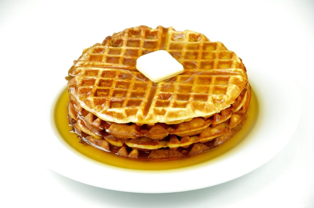 a stack of waffles with butter and syrup. 