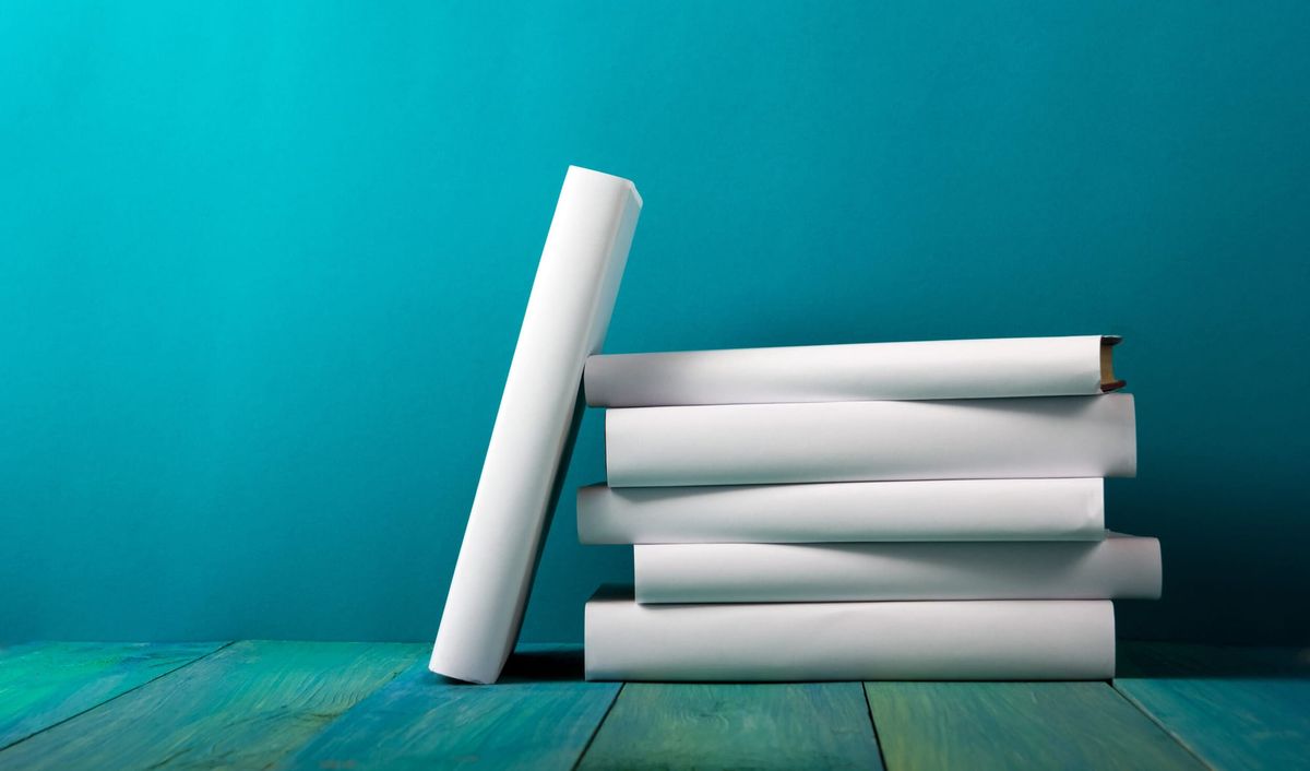 A stack of blank white books against a turquoise background.