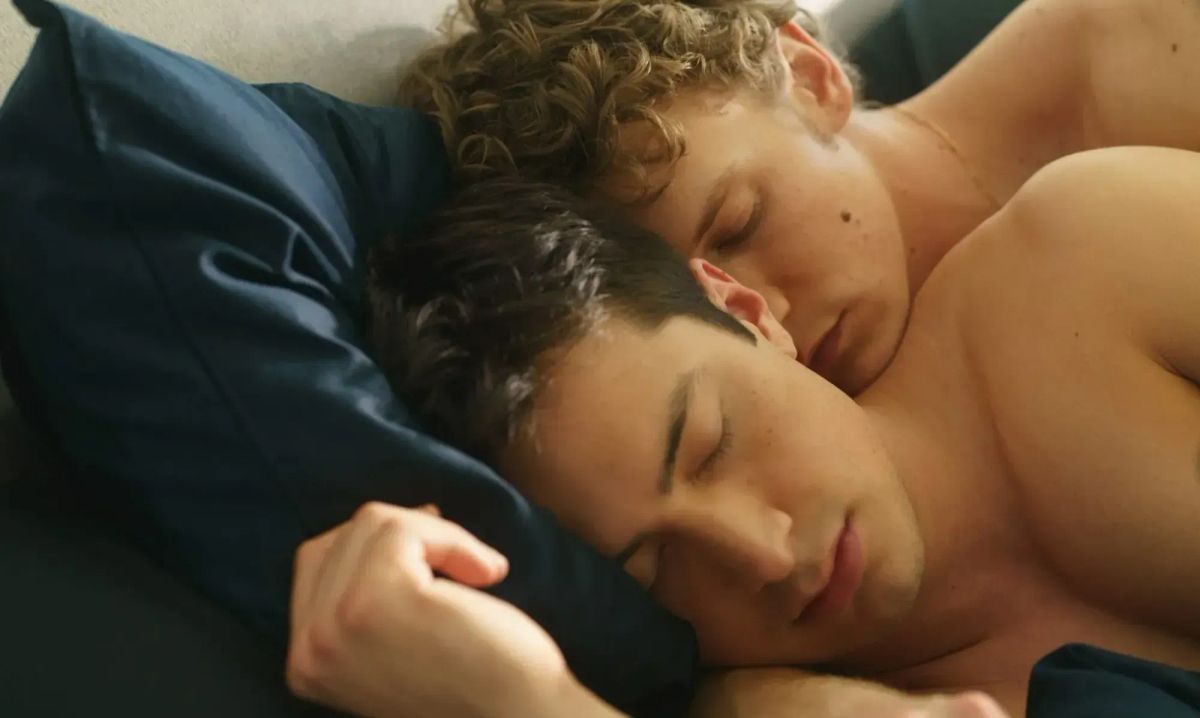 Production still from Heated Rivalry featuring Ilya and Shane laying together naked in bed.