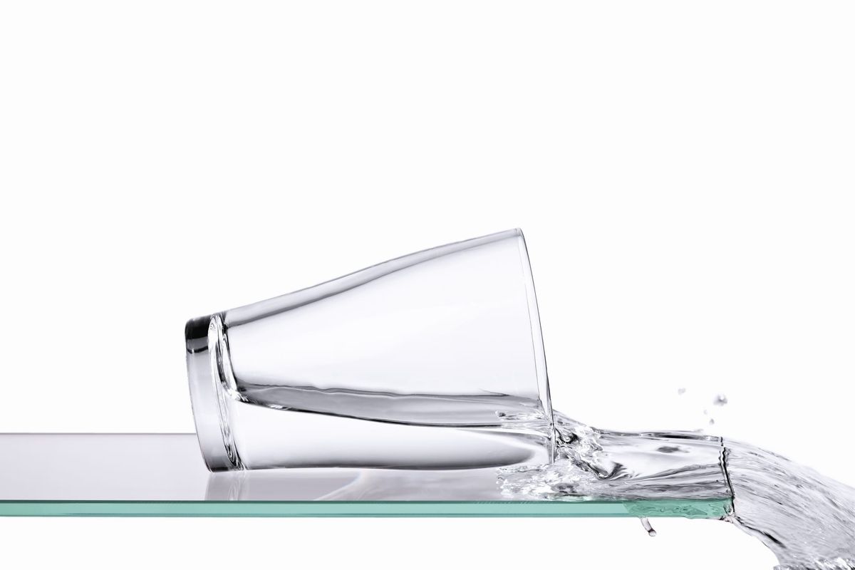 Image of a glass of water spilling over the edge of a glass surface