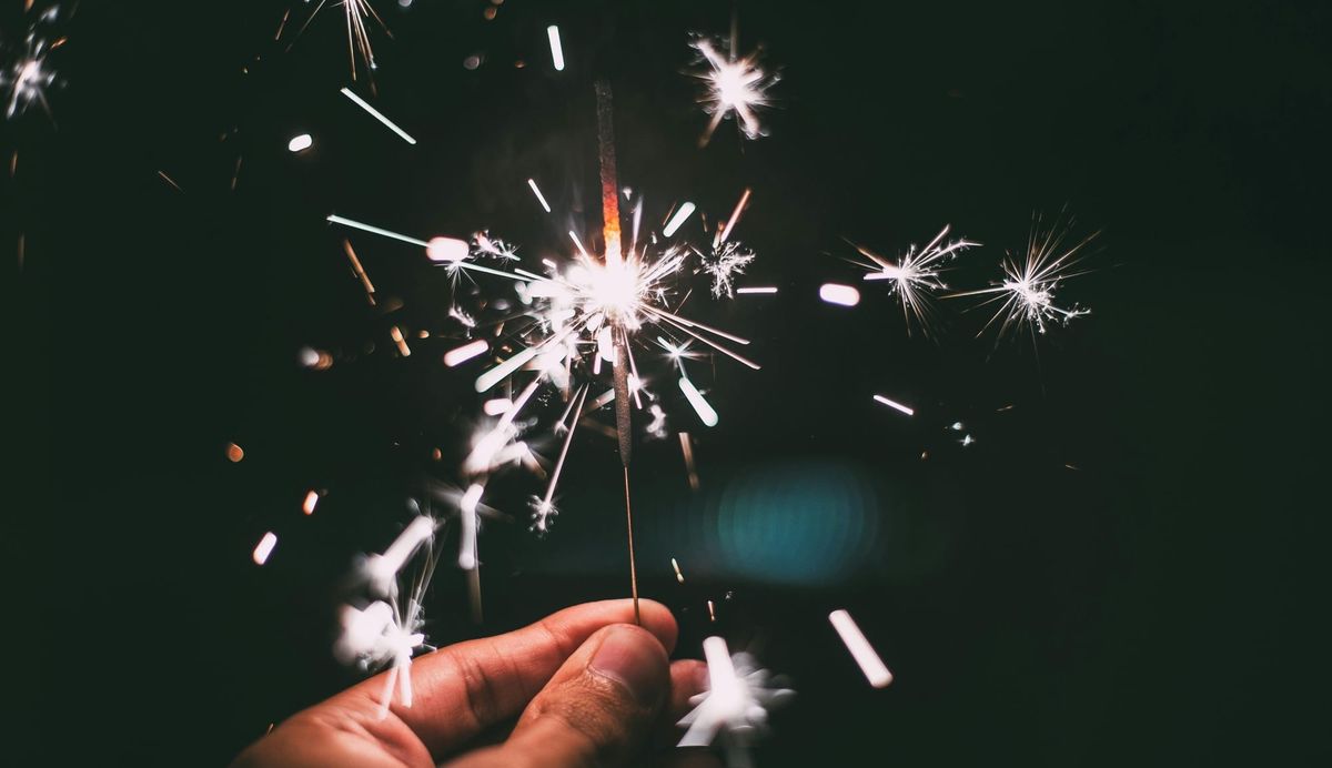 A hand holds a tiny sparkler. 