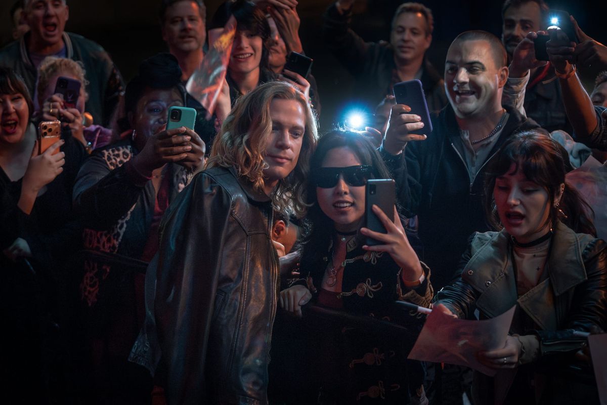 Production still featuring Lestat posing for selfies surrounded by a crowd of fans with their phones out.
