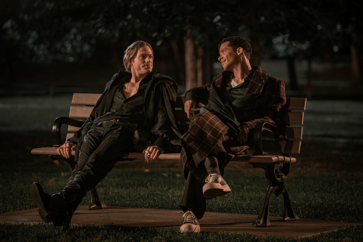 Production still featuring Lestat and Louis sitting together on a bench, gazing into each others' eyes.
