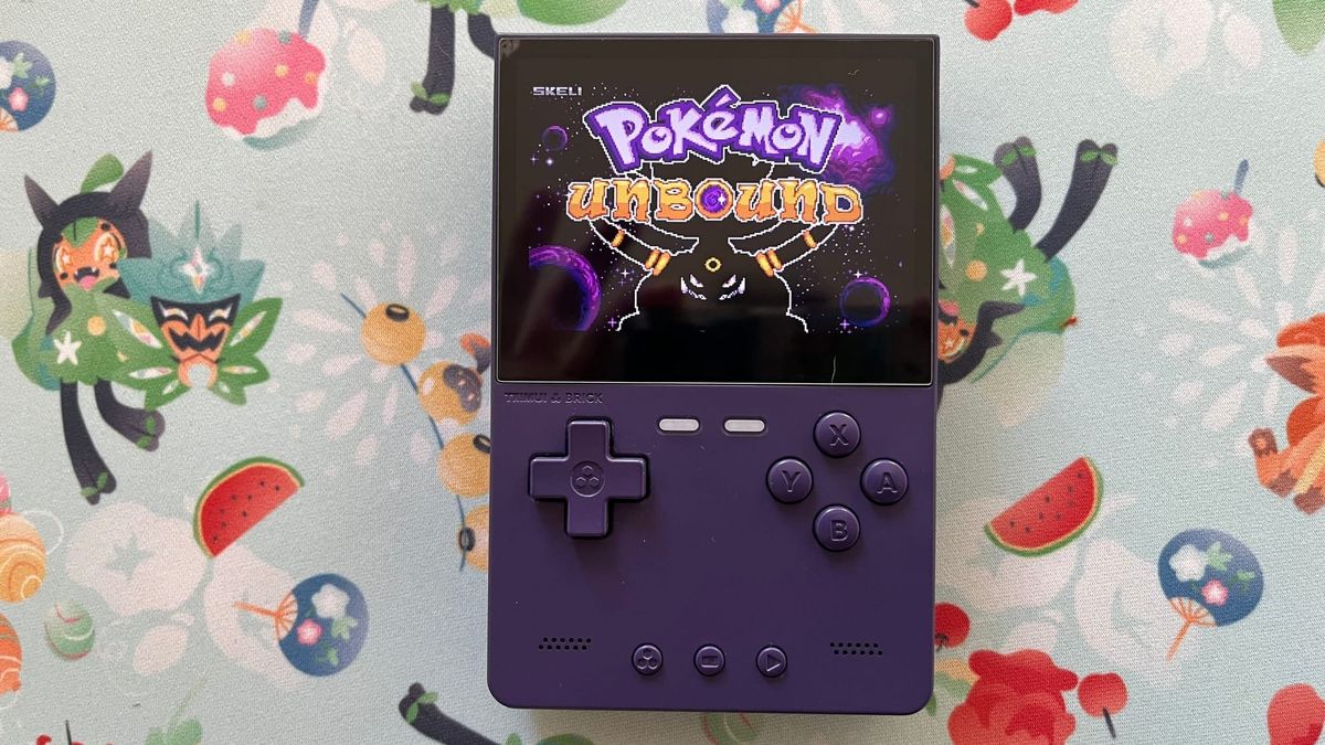 In the center of the image a dark purple gameboy emulator rests flat on an airy light blue Pokémon-patterned fabric, that shows the legendary pokémon Ogerpon in its Teal Mask form.