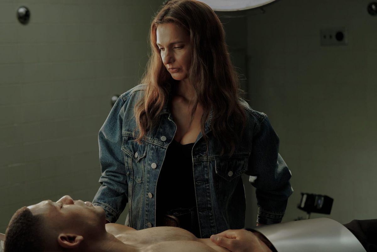 Production still of Zoe healing John as he lays shirtless on a hospital bed.