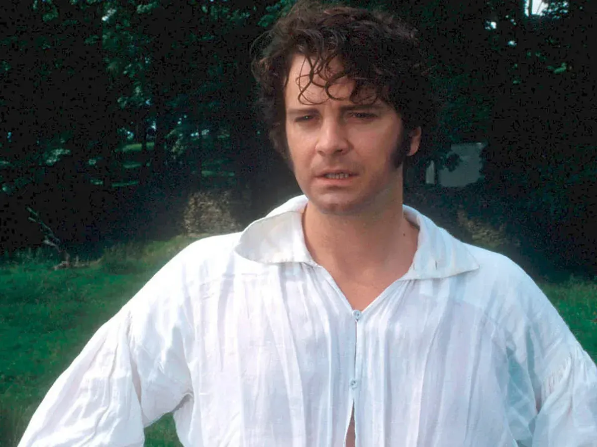 A still image from Pride and Prejudice (1995) of Colin Firth as Mr. Darcy in the famous scene where he appears in a sexy unbuttoned white shirt, wet from a swim, with damp curly hair.