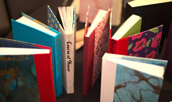 Photograph of a collection of colorful fanbound books, stood up on a table in a semi-circle.