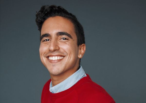 Headshot: Dylan smiling and wearing a red sweater.
