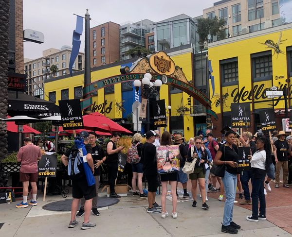 Photograph of the entrance to the Gaslamp Quarter in San Diego with many members of SAG-AFTRA wearing t-shirts and holding strike signs.