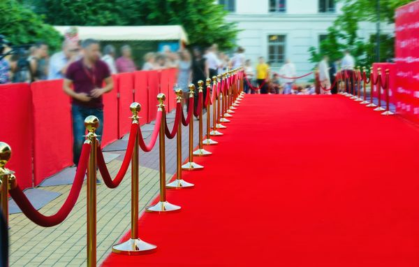 Photograph of a red carpet and a long line of red ropes.