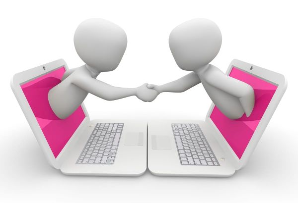 Two faceless white figures coming out of white laptops with pink screens and shaking hands.