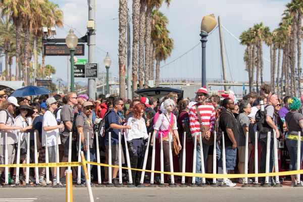Photograph of a crowd of people waiting to cross the street in front of the San Diego Convention Center, many in costume.